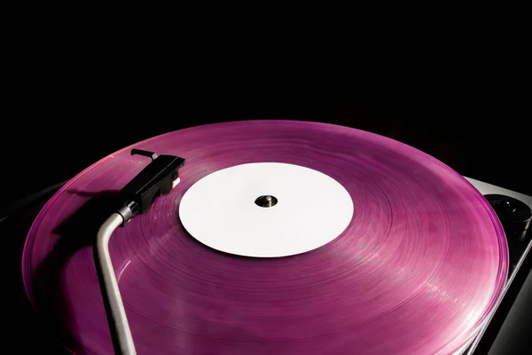 Vintage record player with pink vinyl record on the black background. Old school style.