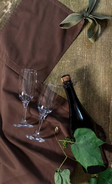 Wine Bottle and Glasses on the wooden background with brown apron. Concept of Delivery Service for Customer.