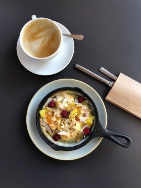 Peynirli kek ya da krep ve böğürtlenli tava, koyu masa üzerinde bir fincan kahve, üst manzara..