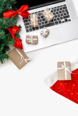 Hediyeli dizüstü bilgisayar, kırmızı şapka, Noel ağacı ve beyaz arka planda paketleme kutuları, üst görünüm, dağıtım konsepti.