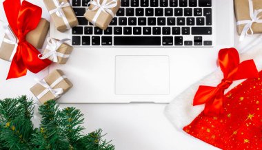 Hediyeli dizüstü bilgisayar, kırmızı şapka, Noel ağacı ve beyaz arka planda paketleme kutuları, üst görünüm, dağıtım konsepti.
