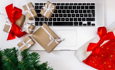 Hediyeli dizüstü bilgisayar, kırmızı şapka, Noel ağacı ve beyaz arka planda paketleme kutuları, üst görünüm, dağıtım konsepti.