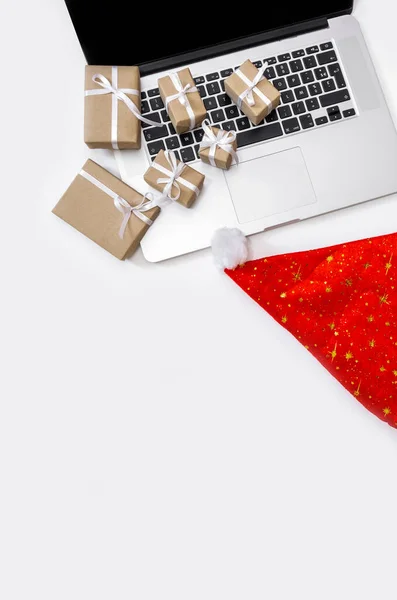Laptop with gifts, red Hat and Packing boxes on the white background, top view, delivery concept.