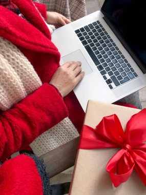 Noel ve yeni yıl arifesinde dizüstü bilgisayar kullanan kırmızı kürklü bir kadın..