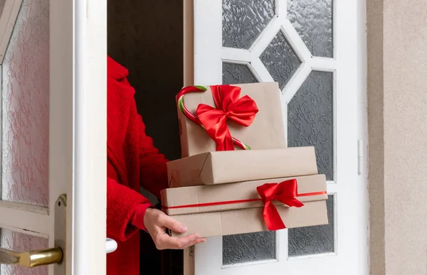 Noel arifesi ve yeni yıl arifesinde, beyaz kapının yanında kırmızı ceketli, hediye kutularını taşıyan bir teslimat..