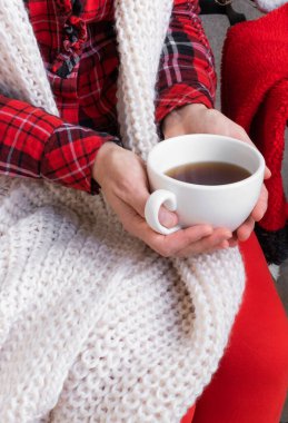 Kadın elleri elinde çay fincanı ya da kahve tutarken kırmızı ve beyaz şenlik kıyafetleri giyer..