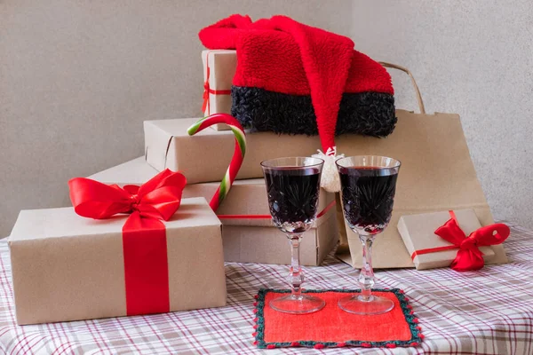 Two glasses with wine stand near shopping bag and gifts on the festive table at home.