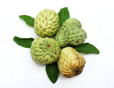 Taze yeşil kremalı elma, elma şekeri, anona cherimola (annona squamosa l.) beyaz arka planda yalıtılmış yapraklarla ikiye bölünmüş meyve. Tropikal egzotik meyve ve sağlıklı meyve