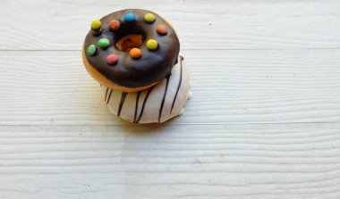 Taze donutlar çok renkli jöleli çikolatalar, renkli çörekler, tatlı renkli çörekler, çikolatalı vanilya kaplı kaplama ahşap masa arkaplanındaki izolasyon.