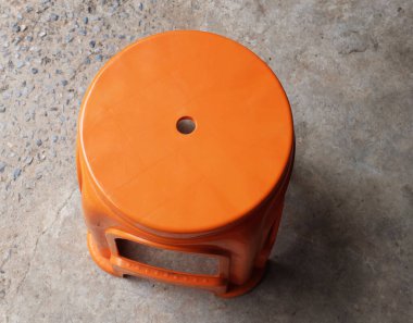 Basit bir turuncu plastik sandalye, turuncu plastik tabure, dinlenmek ve dinlenmek için dinlenmek için sandalyeler, arka bahçe, çimento zeminde izole edilmiş sokak yemekleri.