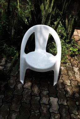 Beyaz plastik sandalye, plastik güneş şezlongları, plastik koltuk, taşa izole edilmiş basit beyaz plastik şezlong. Dinlenme ve dinlenme için dinlenme yerleri, arka bahçe..