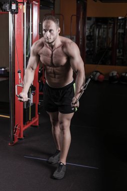 bir adam spor salonunda vücut geliştirme çalışmaktadır, çıtayı yükseltiyor ve kasları trenler.