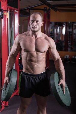 bir adam spor salonunda vücut geliştirme çalışmaktadır, çıtayı yükseltiyor ve kasları trenler.