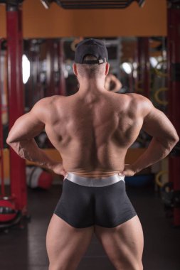 bir adam spor salonunda vücut geliştirme çalışmaktadır, çıtayı yükseltiyor ve kasları trenler.