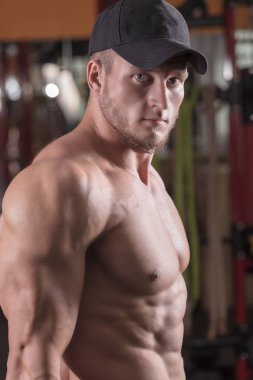 bir adam spor salonunda vücut geliştirme çalışmaktadır, çıtayı yükseltiyor ve kasları trenler.