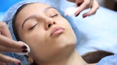 Kozmetik uzmanının resepsiyonunda genç ve güzel bir kız. Kozmetik uzmanı, kadının cilt bakımını yenilemesini sağlar.