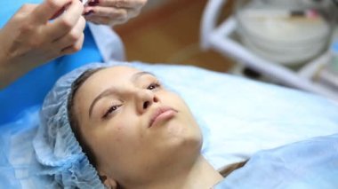 Kozmetik uzmanının resepsiyonunda genç ve güzel bir kız. Kozmetik uzmanı, kadının cilt bakımını yenilemesini sağlar.