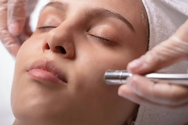 A young and beautiful woman is given a diamond facial cleansing.