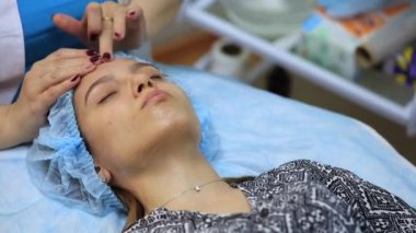 Kozmetik uzmanının resepsiyonunda genç ve güzel bir kız. Kozmetik uzmanı, kadının cilt bakımını yenilemesini sağlar.