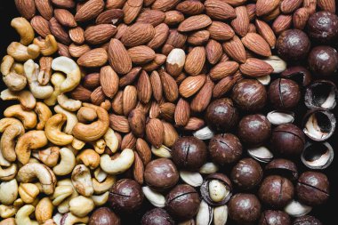 Sağlıklı gıda arka planında çeşitli macadamia fındıkları, badem, kaju fıstığı, fıstık...