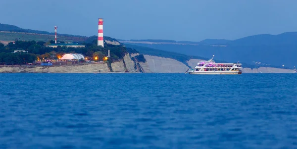 light the beacon at the entrance to the Gelendzhik Bay. Lighthouse at night shines ships in the Black sea.