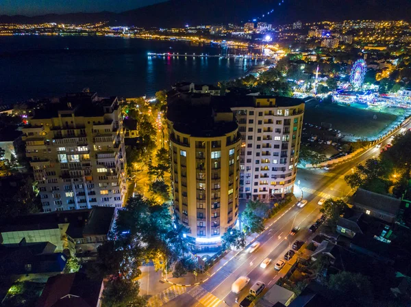 Night Gelendzhik with a bird\'s-eye view. Silhouettes of mountains, promenade, sea, cars with burning headlights illuminate the street. Light in the Windows of buildings. Streets are like rivers of fir
