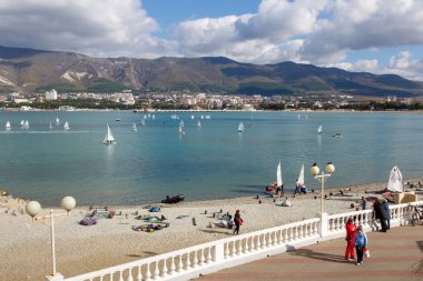 Gelendzhik Beldesi. Yıllık çocuk yat yarışı. Tatil ve dağların arka planda Gelendzhik Körfezi'nde beyaz yelkenli birçok yat. Markoth sırtı. Rıhtımda seyirci, beyaz korkuluk yaslanmış.