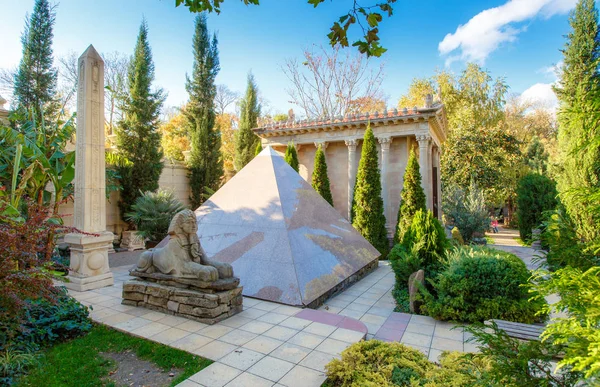 Zeus tapınağının arka planına karşı Mısır Piramidi, Mısır sütunu ve sfenks 'dir. 