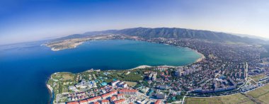 Bir kuş bakışı Gelendzhik Panoraması. Solda Kalın Burun, Gelendzhik deniz feneri ve Gelendzhik Körfezi'nin girişi bulunmaktadır. Arka planda, Kafkas dağları. Şehrin Sağ Orta kesimi