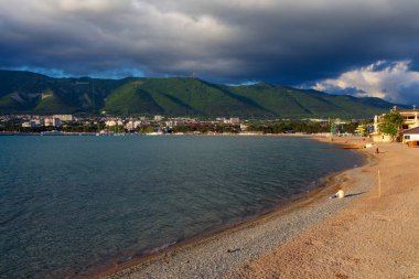 Gelendzhik Beldesi. Sezon sonunda gün batımında kumlu plaj. Dağlardaki bulutlar