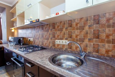 Yeni dekorasyonla birlikte mutfaktayız. Beyaz raflar, mermer tezgah ve bej fayanslar.