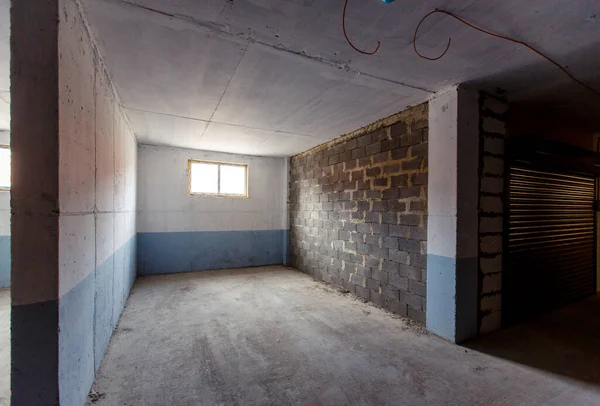 Οι θέσεις στάθμευσης στο υπόγειο μιας πολυκατοικίας χωρίζονται από τοίχους. ορισμένες θέσεις στάθμευσης έχουν ρολά παντζούρια — Φωτογραφία Αρχείου