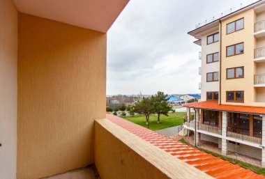 Çok katlı yeni bir apartmanın balkonundan avlu manzarası var. Komşu apartmanın karşısında..