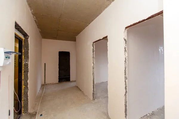 Una pequeña habitación que aún no ha sido terminada. Las habitaciones no renovadas. Nuevo edificio. Las paredes están enlucidas, los pisos son de hormigón. Hay una publicación —  Fotos de Stock