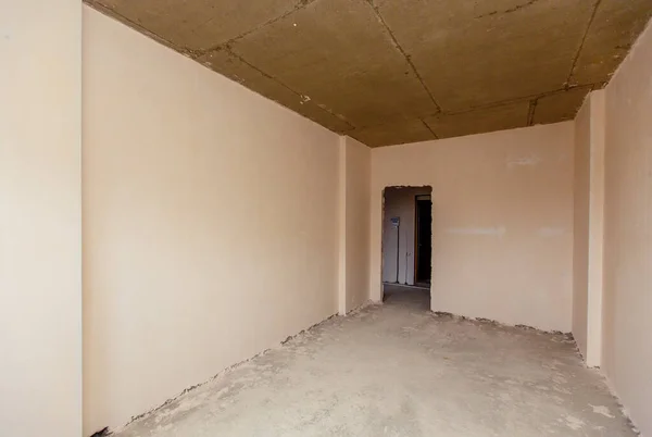 Mały pokój, który jeszcze nie został skończony. Nieodnowione pokoje. Nowy budynek. Ściany są tynkowane, podłogi betonowane. Jest delegacja. — Zdjęcie stockowe