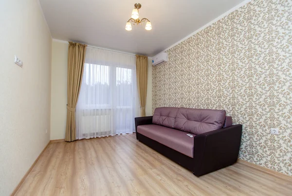 An empty newly renovated room with light Wallpaper, curtains on the Oka and a laminate floor "under the tree". There is a brown sofa against the wall — Stock Photo, Image