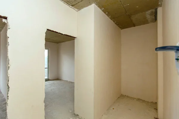 Mały pokój, który jeszcze nie został skończony. Nieodnowione pokoje. Nowy budynek. Ściany są tynkowane, podłogi betonowane. Jest delegacja. — Zdjęcie stockowe