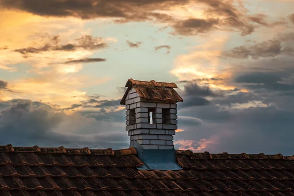 Chimney with white bricks like a little house on the rooftop in the sunset sky