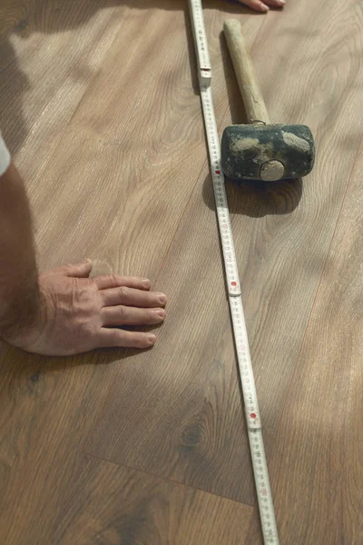 Hand op vers geïnstalleerde laminaatvloer naast rubber hamer a — Stockfoto