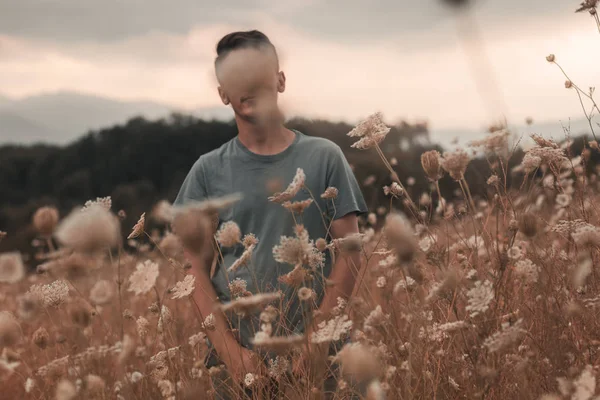 Retrato do homem em pé no campo e cobrindo de flor selvagem — Fotografia de Stock