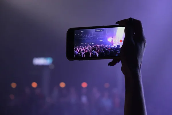 Hand fan with a smartphone shoots a concert