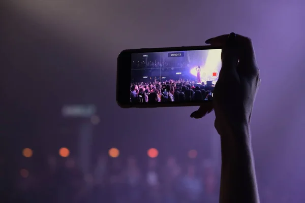 Hand fan with a smartphone shoots a concert