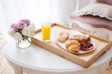 Bir tepsi, yatakta kahvaltı taze sıkılmış meyve suyu ve kruvasan