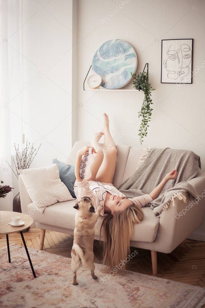 Lovely girl hugging her pug and playing with him in the house