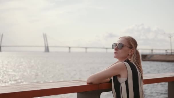 Une femme portant des lunettes de soleil se repose sur le remblai. Concept de vacances 4K — Video