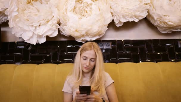 Vista frontale di bella giovane femmina utilizzando il suo telefono cellulare in caffè. Donna che utilizza app su smartphone in caffè in attesa di pranzo e sms sul telefono cellulare — Video Stock