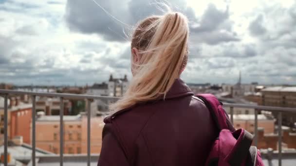 Bevroren vrouw in lederen jas voelt kou terwijl staande op het dak in de wind — Stockvideo