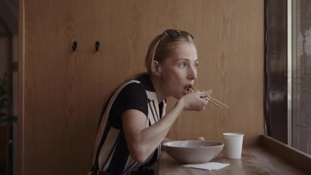 젓가락으로 현지 중국 식당에서 맛 있는 국수를 먹는 백인 여자 — 비디오