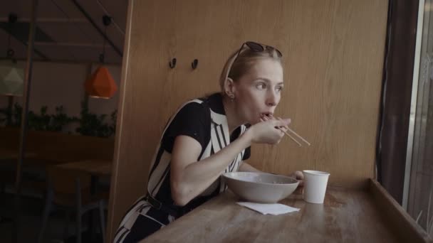 Mujer caucásica comiendo fideos deliciosos en un restaurante chino local con palillos — Vídeos de Stock