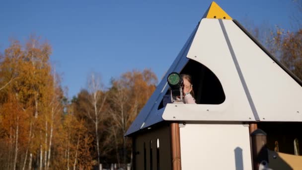 Niño mirando en el horizonte con un telescopio, Niña jugando en el parque, otoño — Vídeos de Stock